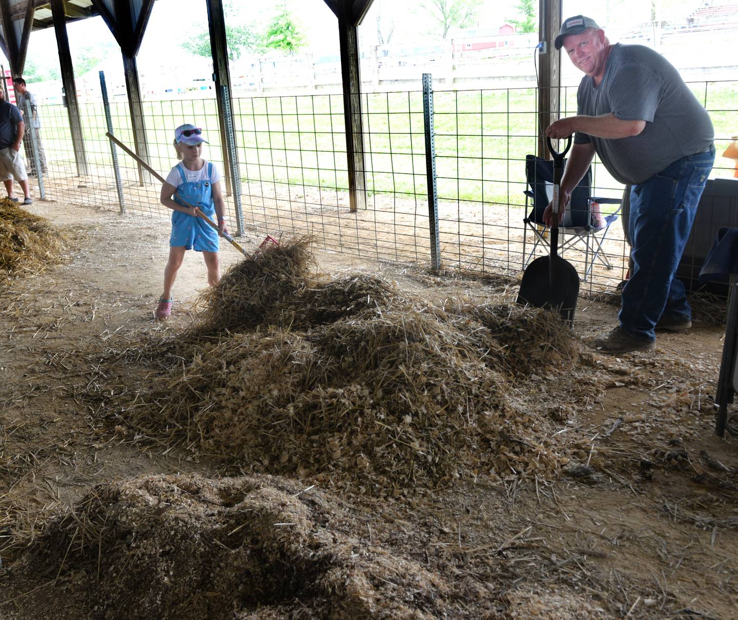 Ryan Byers of Forreston gets help from Alana Smith, 7, of Leaf River, while cleaning the sheep barn at the Ogle County Fair on Sunday, Aug. 6, 2023. The fair ended on Sunday and  ran in conjunction with the Ogle County 4-H Fair.