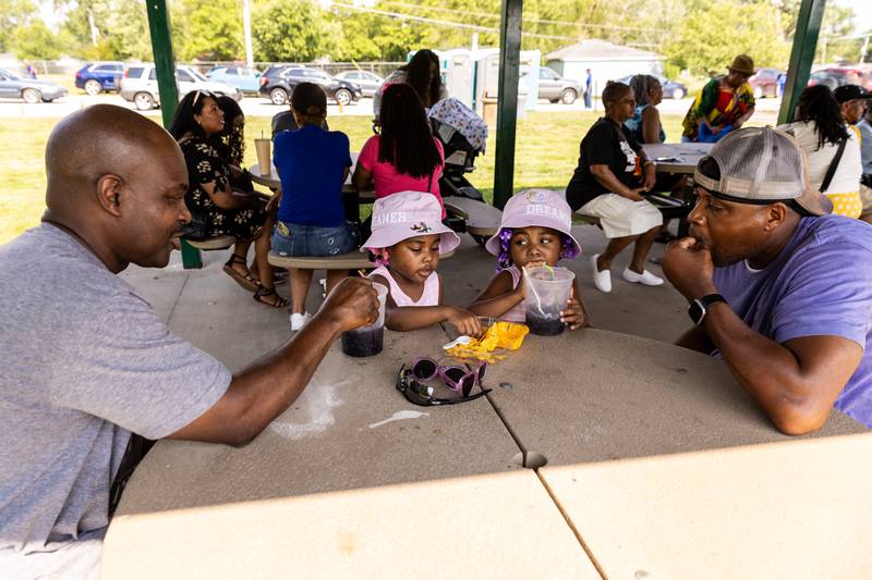 Joliet resident Dexter Morris (from left) enjoys nachos and slushies with Lockport residents Montana (4), Madisyn (4), and Hiram Jordan during Lockport Township Park District's Juneteenth Celebration at A.F. Hill Park on June 19, 2024.