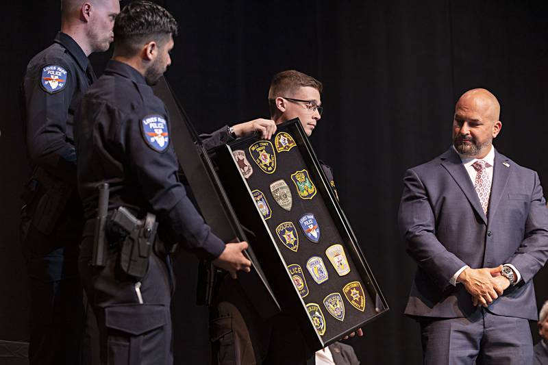 Graduates present director LaMendola with a shadow box of patches from the departments the recruits will be working for Friday, April 14, 2023.