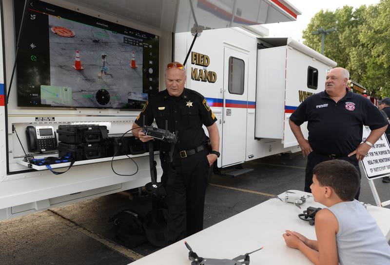 Westmont Police Sergeant Mike Weibler and Fire Chief, Dan Mejdrech demonstrate the use of a drone that assists with tracking for families and children including Elmhurst resident Kian Roohani during the National Night Out on Tuesday, Aug 1, 2023.