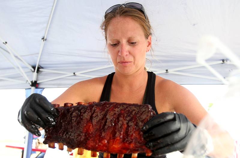 Renaee French of Peru, takes her rack of ribs off of the grill during the BBQ and Blues festival on Friday, Sept. 13, 2024 downtown La Salle.