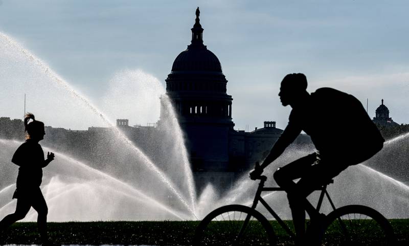 FILE - The Capitol is seen as water sprinklers soak the National Mall on a hot summer morning in Washington, July 15, 2022. A new poll finds that most Americans share many core values on what it means to be an American despite the country’s deep political polarization. The poll from The Associated Press-NORC Center for Public Affairs Research found that about 9 in 10 U.S. adults say the right to vote, the right to equal protection under the law and the right to privacy are important or very important to the U.S.’s identity as a nation.(AP Photo/J. Scott Applewhite)