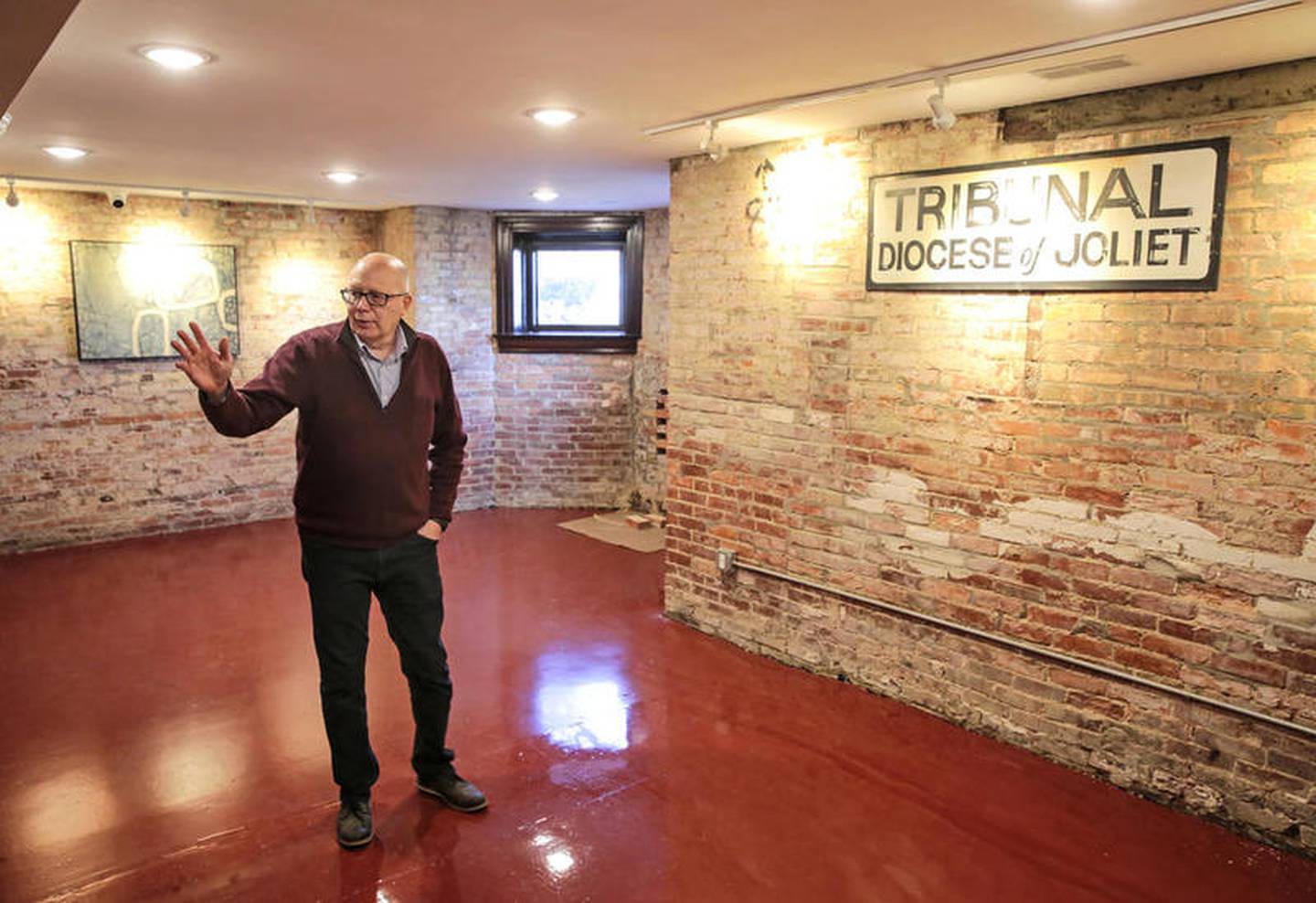 In the basement of the former Bishop's house, Phil Soto shows a diocese tribunal sign on one of the walls of exposed brick. "That was the original sign on the front of the building," he said.