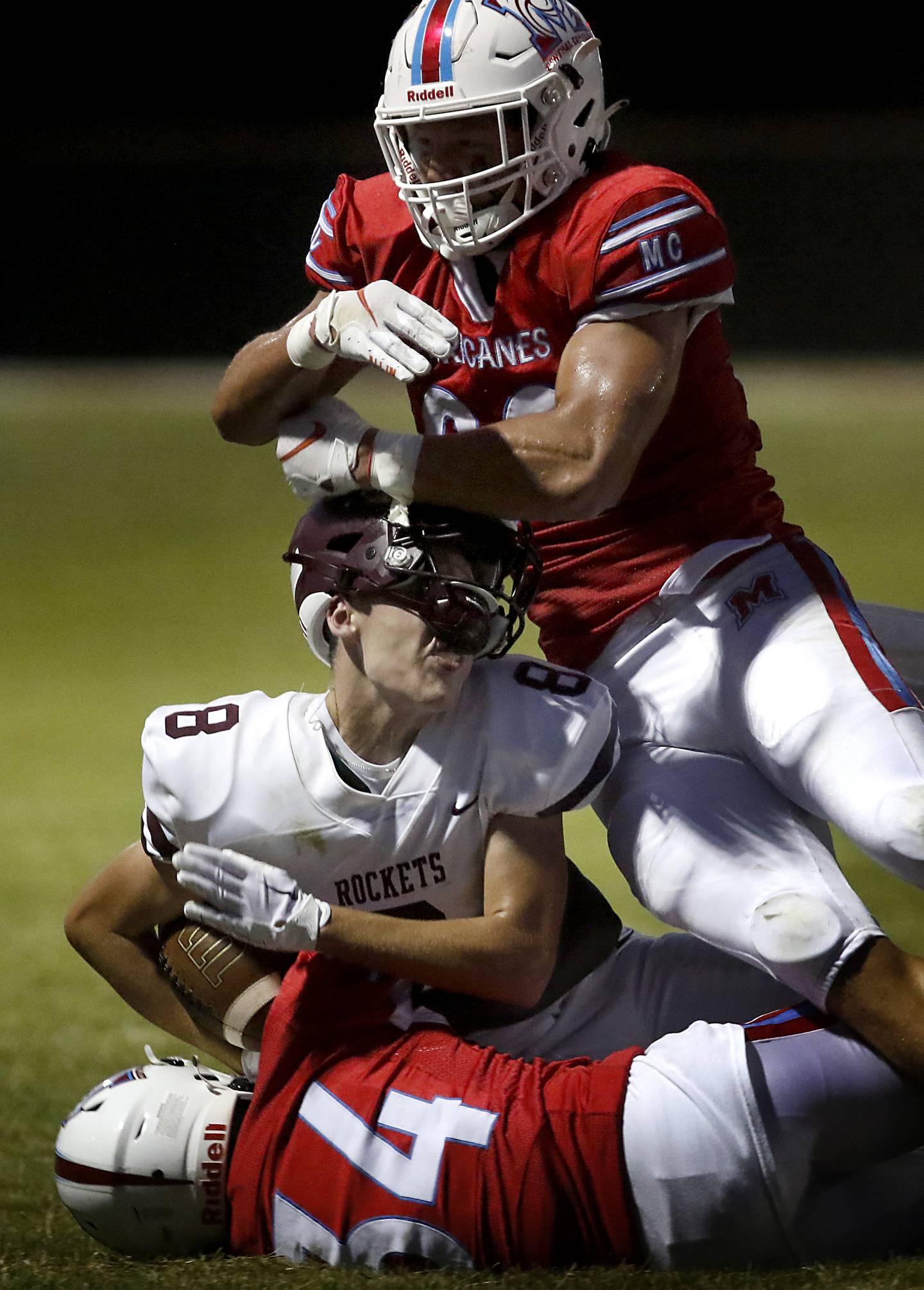 Marian Central's Christian Bentancur pulls Richmond-Burton's Jack Martens’ helmet off as Martens is tackled by Steven Sarfo and Bentancur during a nonconference football game Friday, Aug. 25, 2023, at Marian Central Catholic High School.