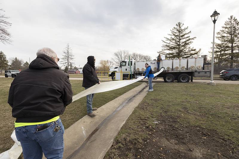 Coloma Park District director Tom Henry, right, helps unroll the chute for the trout stocking Tuesday, March 21, 2023 at Centennial Park in Rock Falls.