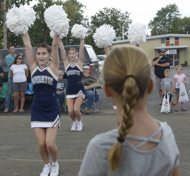 The Marquette High School cheerleaders stop and do a cheer for the crowd during the Community Fest Parade Sunday in Grand Ridge.