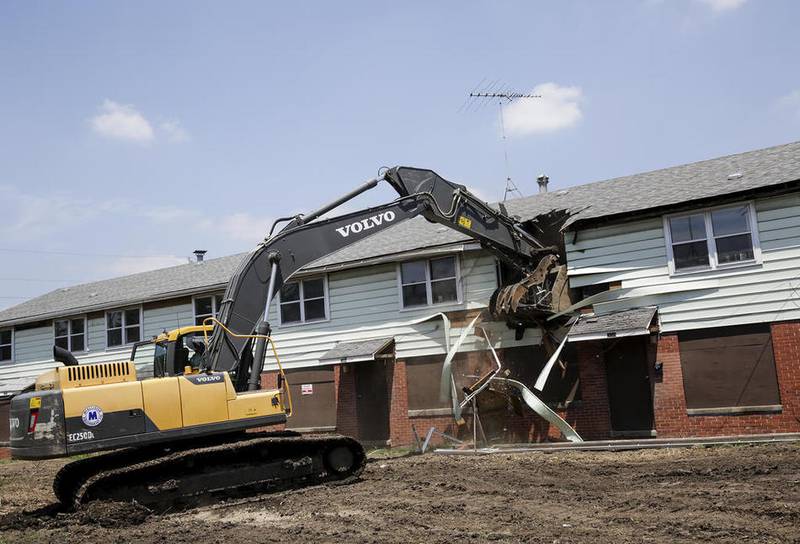 An excavator demolishes a Des Plaines Garden housing unit Friday during a demolition ceremony for the  Joliet public housing complex.