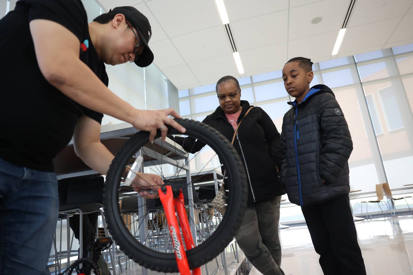 Carter Davis, right, stands with his grandmother Pam Watkins as his bike is being repaired during the Repair Cafe event at the Joliet Junior College Romeoville campus on Saturday, April 13, 2024.