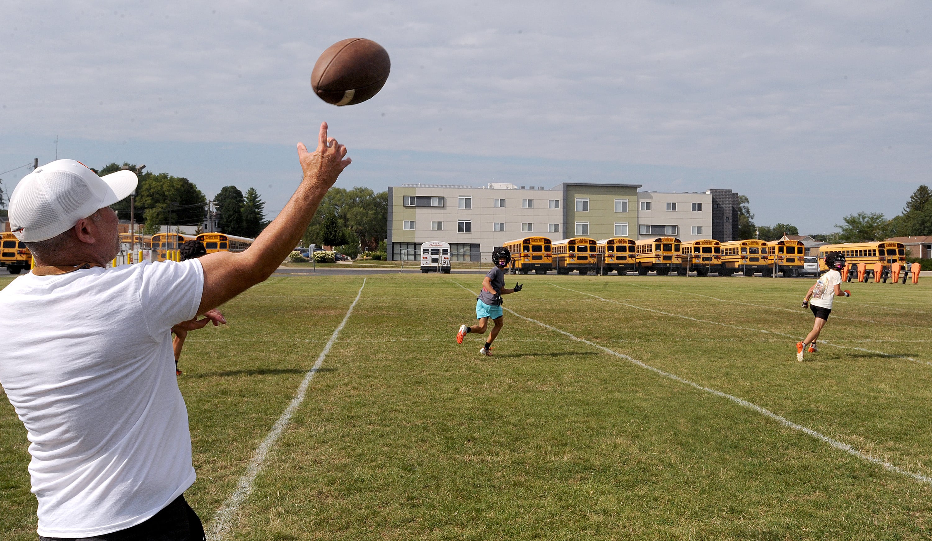 Assistant football coach Jason Van Pelt throws a pass during a passing drill on the first day of football practice at Sandwich High School on Monday, Aug. 12, 2024.