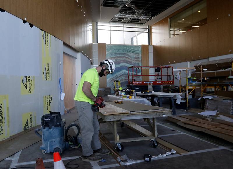 A construction worker installs paneling in the lobby on Friday, April 21, 2023, as construction continues on the new Mercyhealth hospital in Crystal Lake. The hospital is ramping up hiring as it gets set to open in this summer.