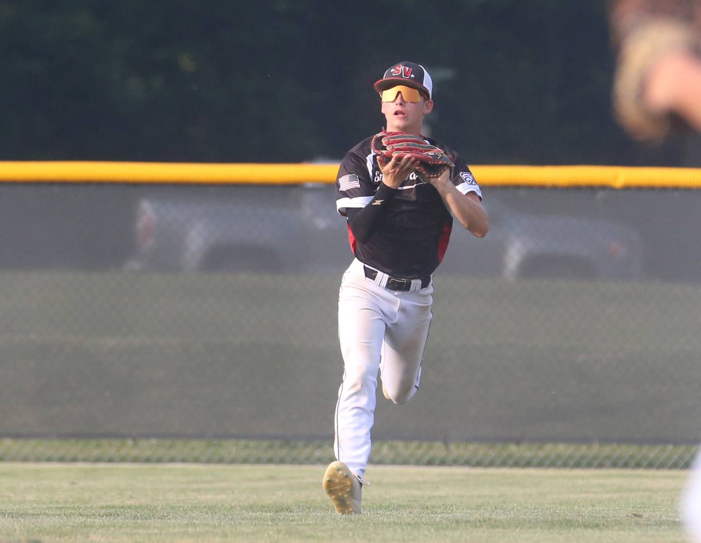 Spring Valley center fielder Jaxson Pinter squeezes the ball to make the final out of the third inning during the Central Region Baseball Tournament on Monday, July 24, 2023 at Washington Park in Peru.