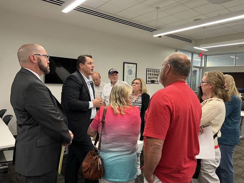 DeKalb County Administrator Brian Gregory, standing next to DeKalb County assistant State's Attorney David Berault, talks to Dawn Graves, Mike Ostrom, Amanda Walter and others about the pending sale of the DeKalb County Rehab and Nursing Center after a public hearing was held in DeKalb on July 11, 2023 pertaining to the last major process left before the deal can close.