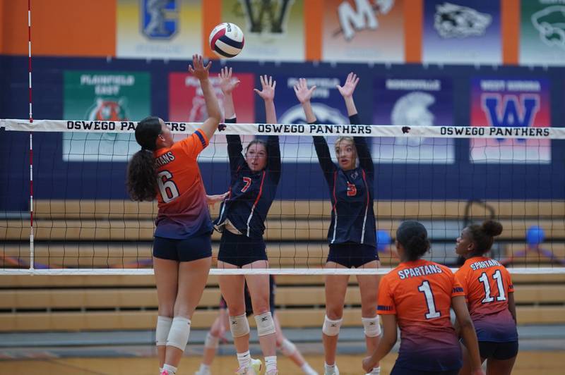 Oswego’s Kelsey Foster (7) and Riley Borrowman (3) defend the net against a kill attempt by Romeoville's Lianna Ortiz (6) during a volleyball game at Oswego High School on Tuesday, Oct. 17, 2023.