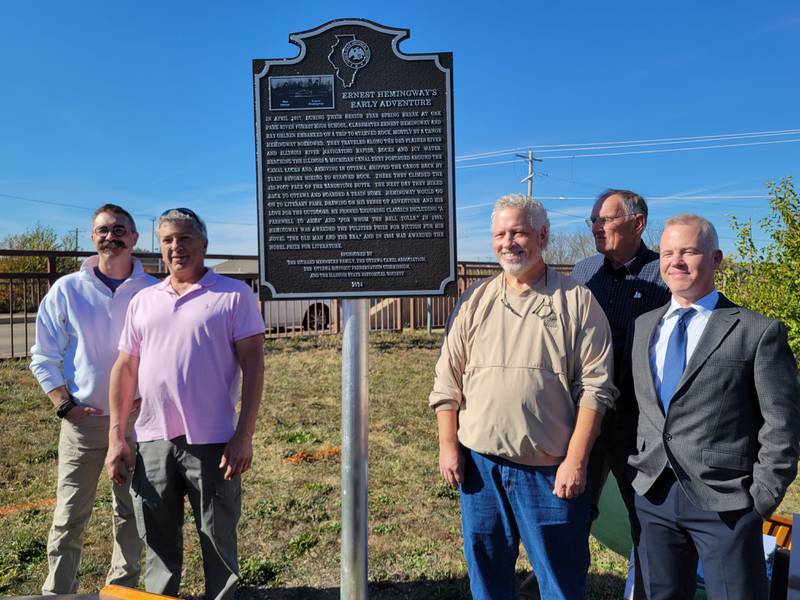 Standing beside the marker commemorating Ernest Hemingway and Ray Ohlsen's 1917 trip to Ottawa are (from left) Ottawa Mayor Robb Hasty, Ottawa Historical Preservation Commission member and marker purchaser Richard Mennecke, Ohlsen's grandson Andy Rae, Ottawa Canal Association president Arnie Bandstra and Chet Wold of the Illinois Historical Society.