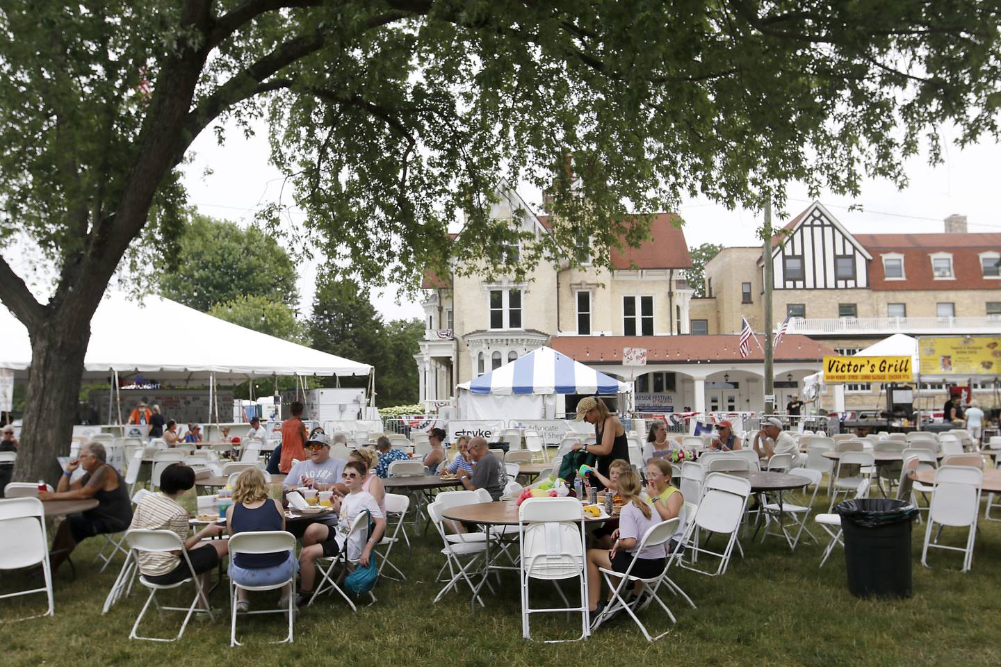 People eat in the shade during Lakeside Festival Friday, June 30, 2023 at the Dole and Lakeside Arts Park in Crystal Lake.