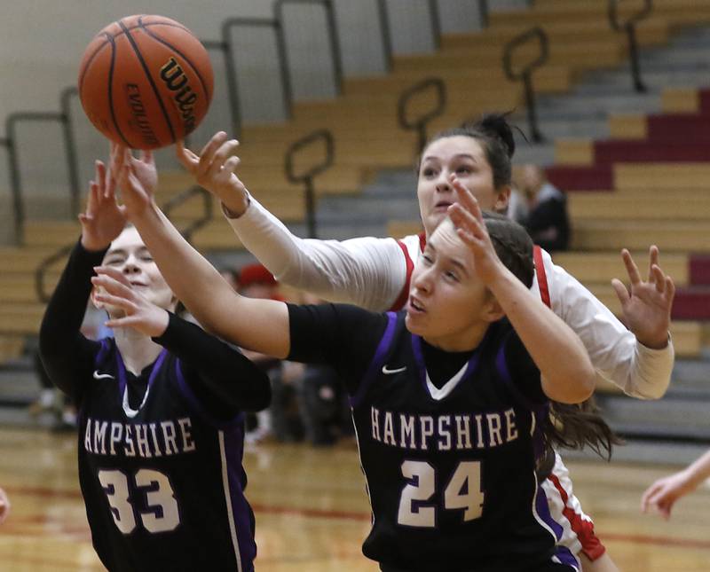 Huntley's Ashlyn Horton (center) reaches over Hampshire's Ashley Herzing and Whitney Thompson to knock a rebound away during a Fox Valley Conference girls basketball game Monday, Jan. 30, 2023, at Huntley High School.