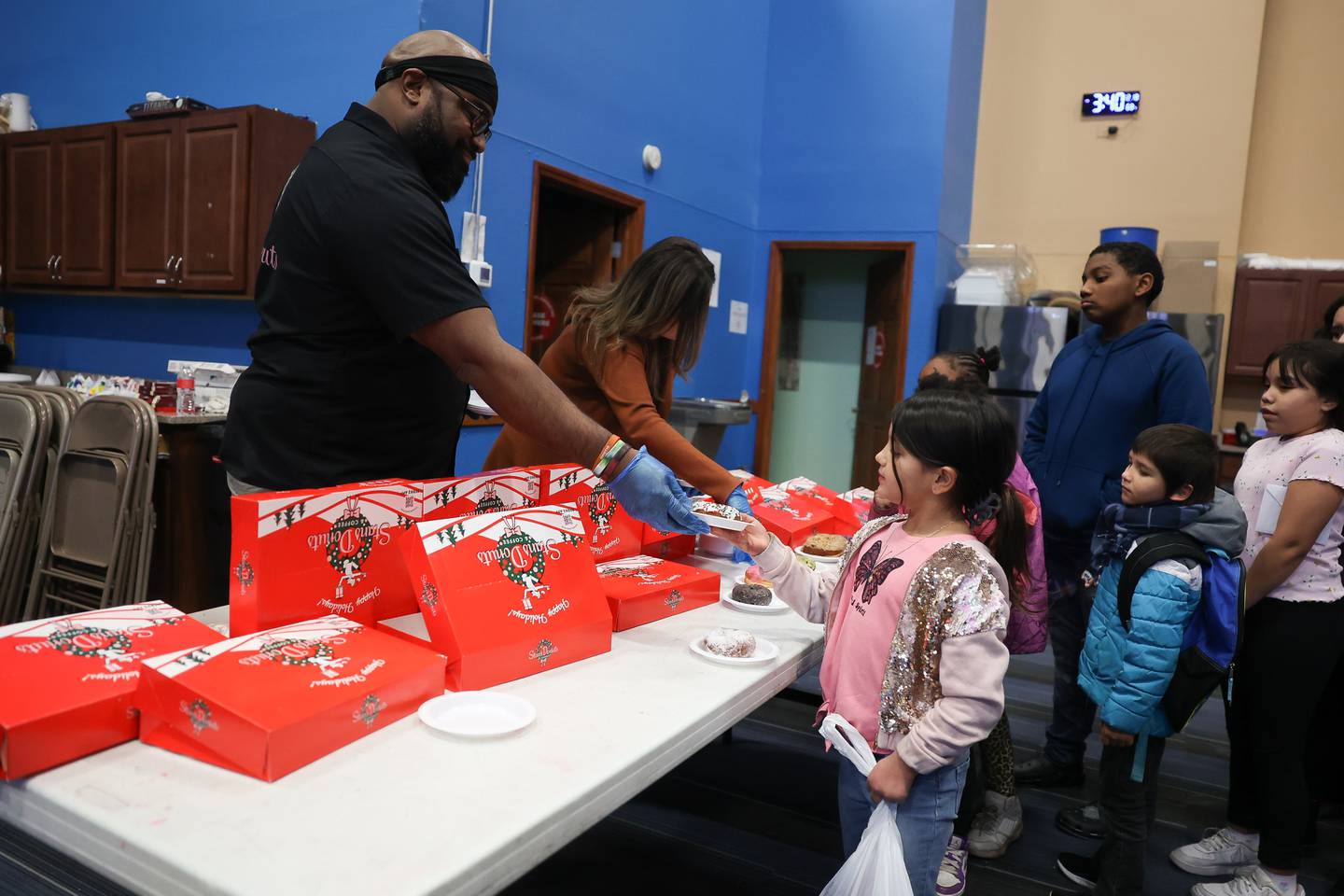 Dion Williams, general manager of Stan’s Donuts Oak Brook Terrace, hands out donuts to the children at the Boys & Girls Club Joliet pizza party on Saturday, Dec.18, 2023.