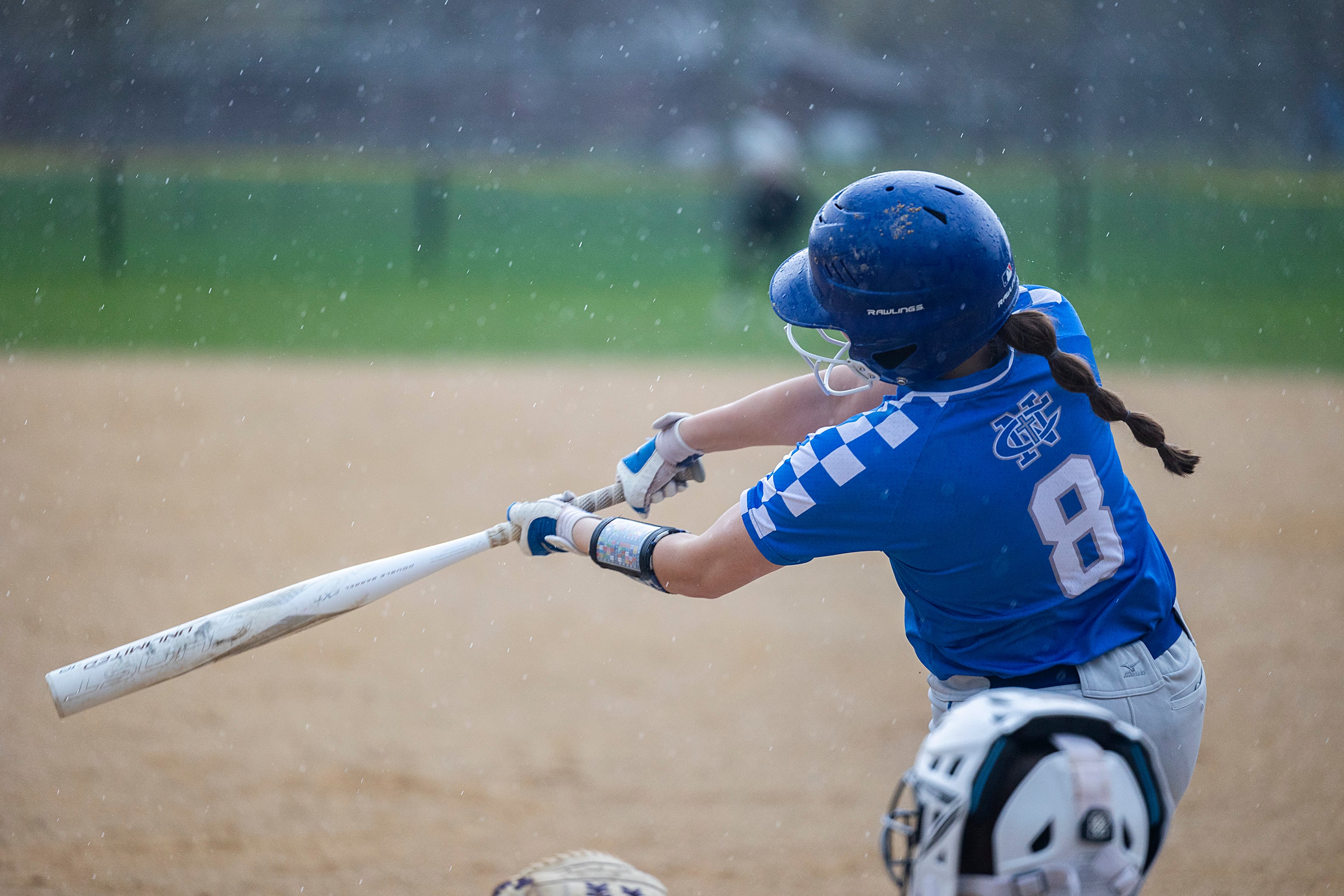 Newman’s Lucy Oetting drives connects for a hit as the rain starts to fall against Dixon Thursday, April 11, 2024 at Reynolds Field in Dixon.