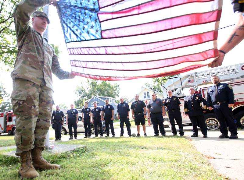 Army Pvt. Damien M. Presthus and La Salle County Sheriff's deputy and former United States Marine Johnny Godnia unfold a flag during a 9/11 Memorial Service on Wednesday, Sept. 11, 2024 at Circuit Breaker School in Peru. Firefighters police officers and paramedics from La Salle, Peru, and Hennepin participated in the memorial service.