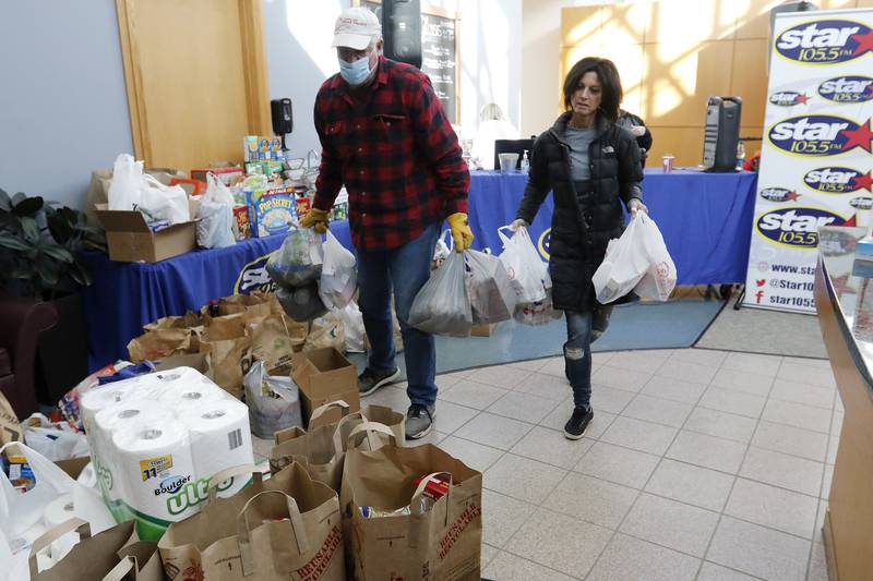 Crystal Lake Food Pantry food rescue volunteer Paul Georgy, left, and food rescue manager Tanya Hill carry donations of food during a Community Harvest food drive Friday, Nov. 19, 2021, at Northwestern Medicine Health and Fitness Center in Crystal Lake. About 40 sponsoring sites helped contribute to the annual food collection and donation campaign for the Crystal Lake Food Pantry.