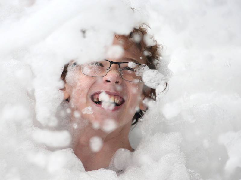 Dylan Kelly of Spring Valley smiles as he submerges his body underneath a large foam pit during  the National Night Out event on Tuesday, Aug. 6, 2024 at Kirby Park in Spring Valley.