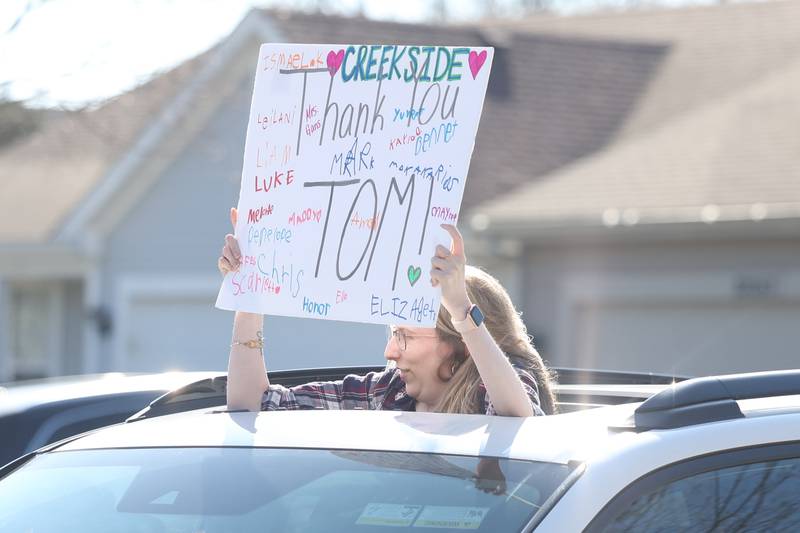 A lady holds up a sign as the car she is riding in passes by Tom Hernandez at a drive-by parade in his honor on Saturday, March 16, 2024 in Plainfield.