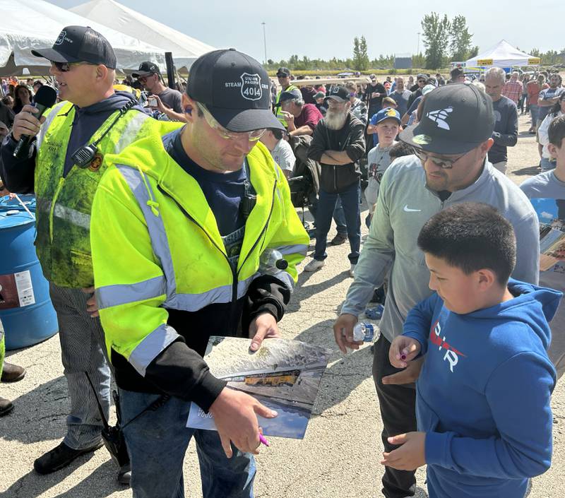 Dominick Rodriguez, 9, and his dad Cervanto, of Posen, Illinois, get a UP calendar signed by one of the a "steam team" members that operate the Union Pacific's Big Boy 4014 vintage steam locomotive. An estimated 61,000 people visited the steam locomotive at the UP Global II terminal on Sunday, Sept. 8, 2024 during the daylong, free event in Rochelle.