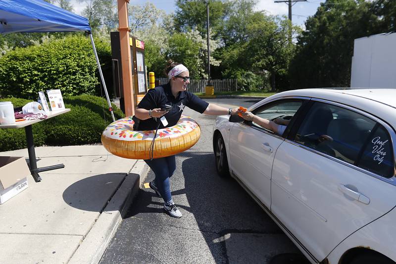 McHenry Police Public Information Officer Ashley O'Herron hand a coupon for a free donut to a customer during the Cop on a Rooftop fundraiser for Special Olympics Illinois on Friday, May 17, 2024, at the Dunkin Donuts at 4502 Elm Street in McHenry. Law enforcement officers spent their morning raising funds and awareness for Special Olympics Illinois and the Law Enforcement Torch Run.