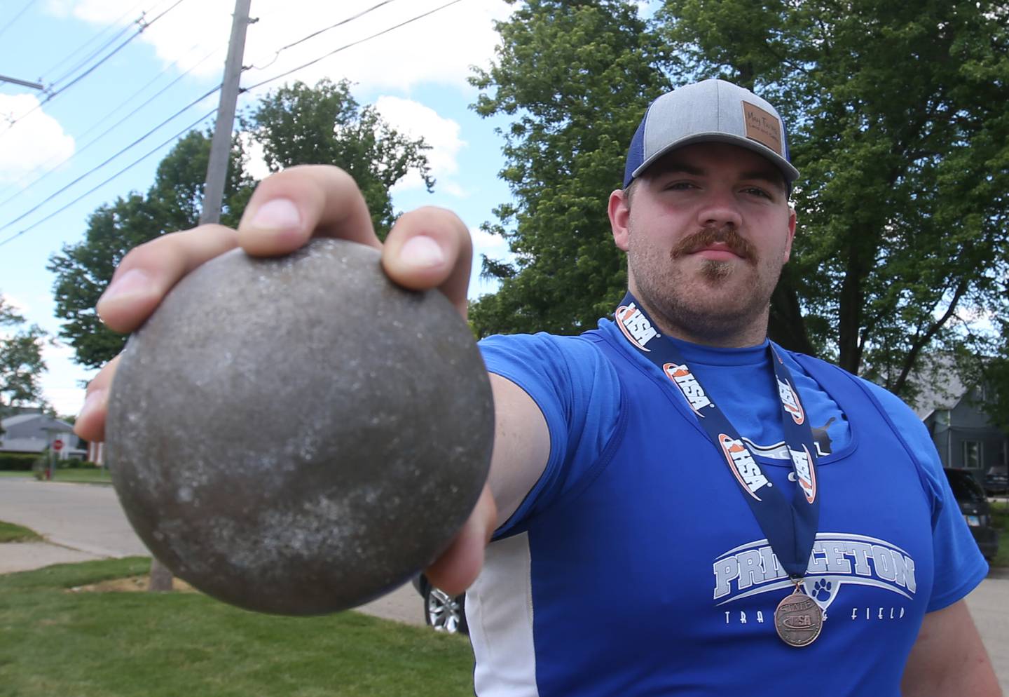 Princeton's Payne Miller poses for a photo with his shot put ball in the throwing area on Wednesday, May 29, 2024 at Princeton High School. Miller is the NewsTribune boys track athlete of the year.