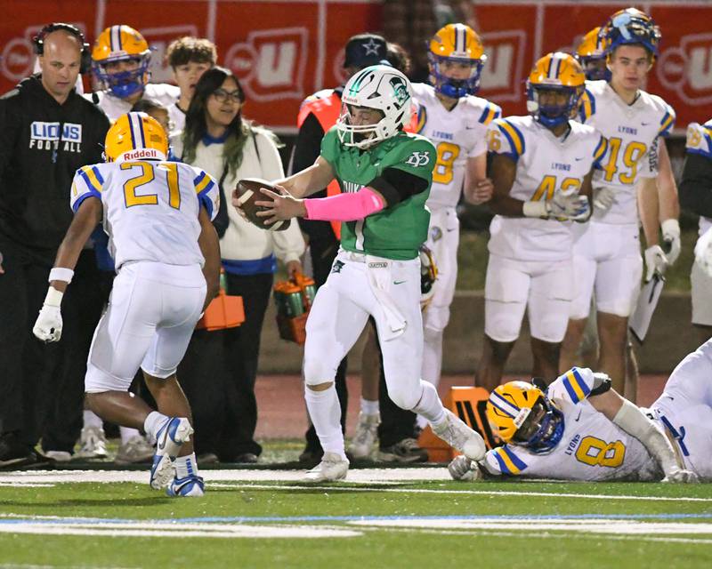 York High School Bruno Massel runs the ball for a first down before being pushed out of bounds by Lyons Township's Shane Harris (21) and Pat Cheney (8) on Friday Oct. 18, 2024, held at York High School in Elmhurst.