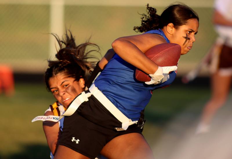 Dundee-Crown’s  Skyler Noe, front, gets past Jacobs’ Amy Trejo in varsity flag football on Tuesday, Sept. 3, 2024, at Dundee-Crown High School in Carpentersville.