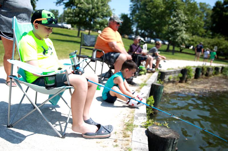 (Left to right) Kian O’Toole, 9, Kelvin O’Toole, 7, and their grandfather, Ted Thilly, all of Wheaton fish at Herrick Lake Forest Preserve during the DuPage Forest Preserve Police Cops and Bobbers event in Wheaton on Wednesday, June 19, 2024.