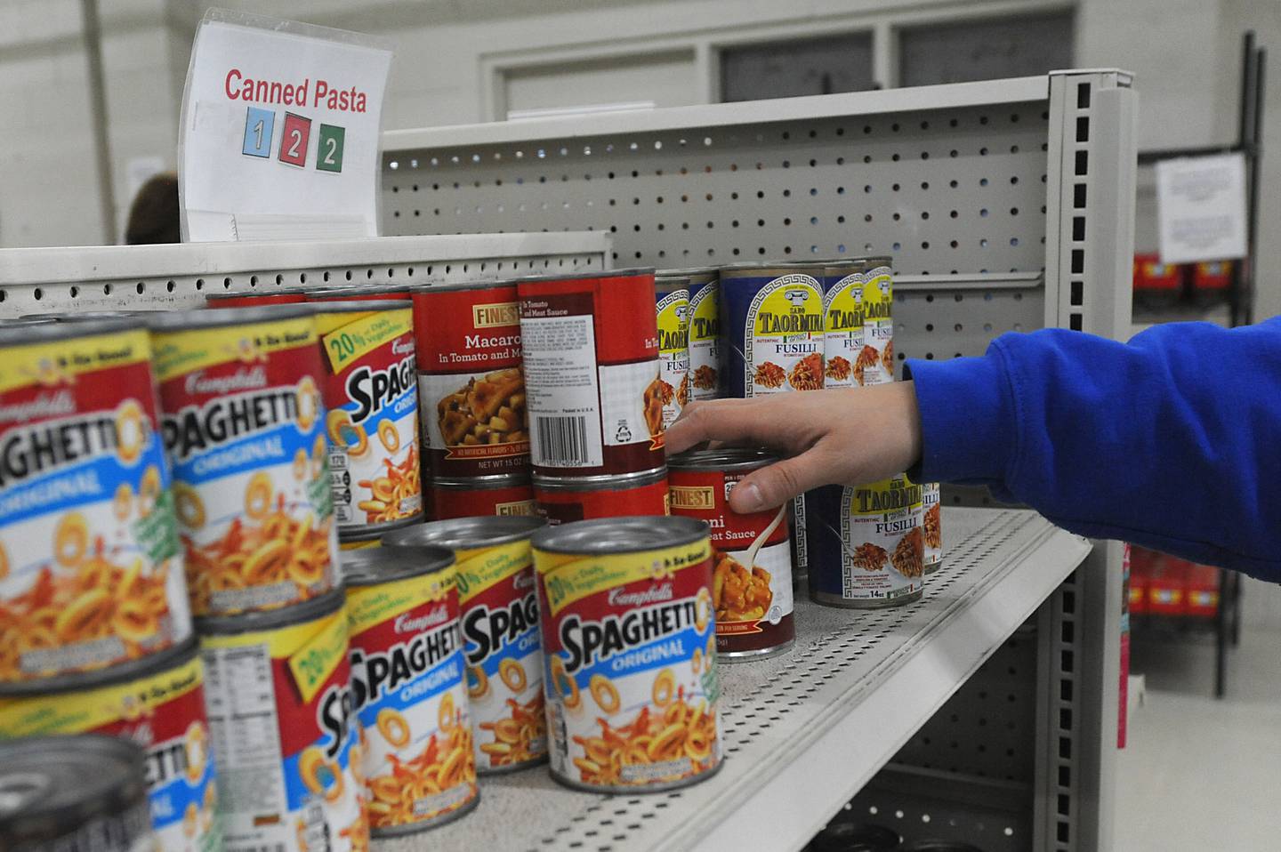 A person grabs a can of food from a shelf as they shot for food Monday, April 25, 2022, at the Crystal Lake Food Pantry, 42 East Street, in Crystal Lake. Food pantries across McHenry County are combating both inflation and increasing need.