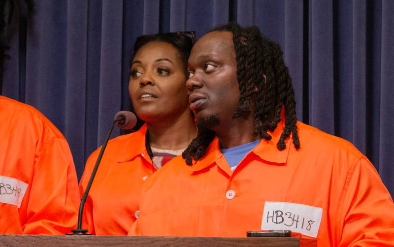 Antonio Lightfoot, deputy director at the nonprofit Workers Center for Racial Justice, speaks at a news conference in the Illinois State Capitol. Advocates wore orange jumpsuits to symbolize the restrictions placed on people who return to society from prison.