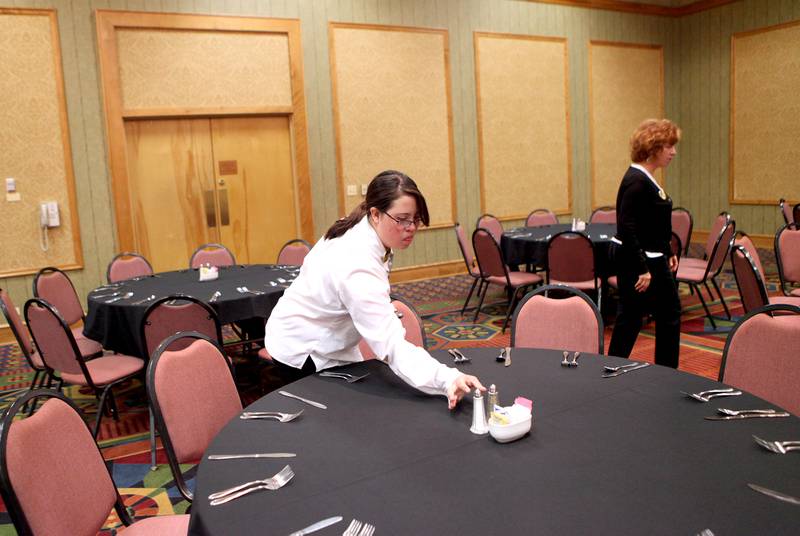 St. Charles East student Nikita Chavez places salt and pepper on a table in preparation for a luncheon for 450 guests at Pheasant Run Resort in St. Charles Wednesday morning. Chavez is a part of the school's community-based vocational training program.