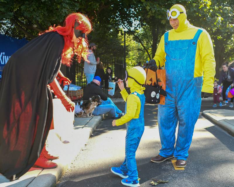 Tefik Sulo is all smiles watching his son Anwar sulo, 4 years old, of Elmhurst receive a treat from Batwoman, Natalie Kope from Lions and works with with Leagues of Enchantment, during the Family Fall Fest held at Wild Meadows Trace Park in downtown Elmhurst on Saturday Oct. 7, 2023.