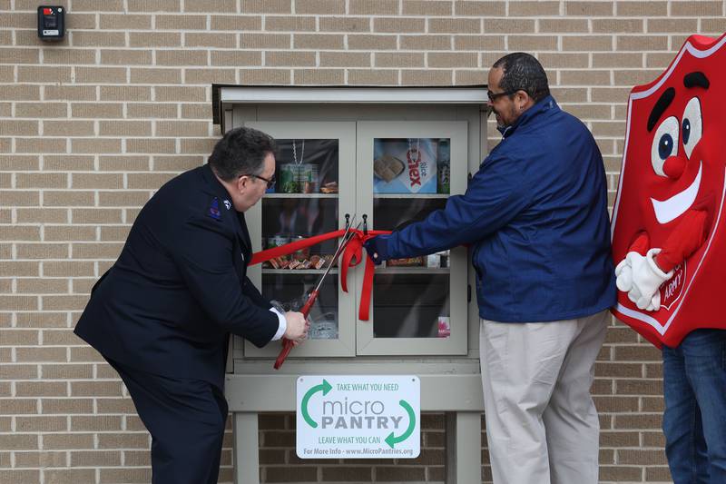 Robert Dutton, Equity Manager for Will County Health Department and Community Health Center, assists Scott Hurula, Administrator at The Salvation Army of Joliet, as he cuts the ribbon at the Salvation Army Joliet Corps Community Center micro pantry ribbon cutting ceremony on Friday Mar. 1st, 2024 in Joliet.