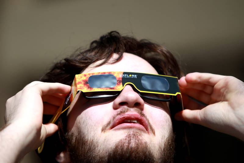 Waubonsee Community College student Gavin Roberts looks at the sun using special protective glasses during the solar eclipse on Monday, April 8, 2024 at the college’s Sugar Grove campus.