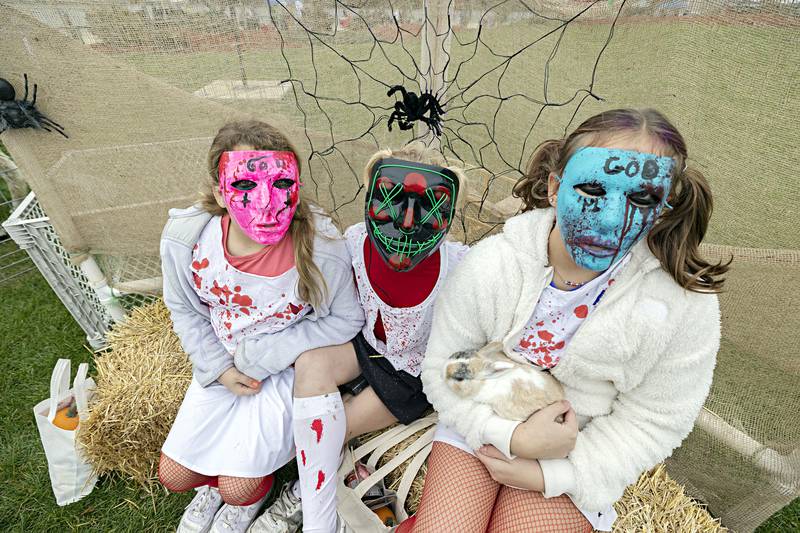 Donning creepy masks, Maci Kramer (left), 11, Jaycelyn Preston, 9, and Kendal Poff, 11, pose for pictures with a bunny from P&C Little Rascals Friday, Oct. 27, 2023 in Rock Falls.