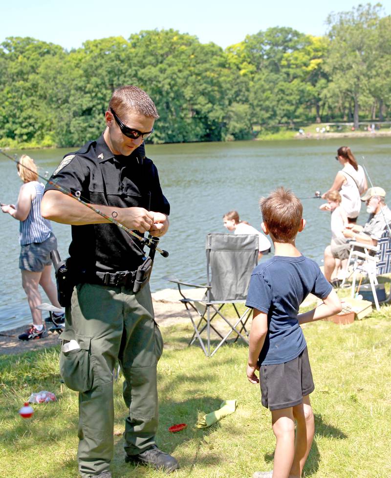 DuPage Forest Preserve Police Sgt. Krist Schroeder helps Noah Whalen, 8, of Clarendon Hills with his fishing line and bait at Herrick Lake Forest Preserve during the DuPage Forest Preserve Police Cops and Bobbers event in Wheaton on Wednesday, June 19, 2024.