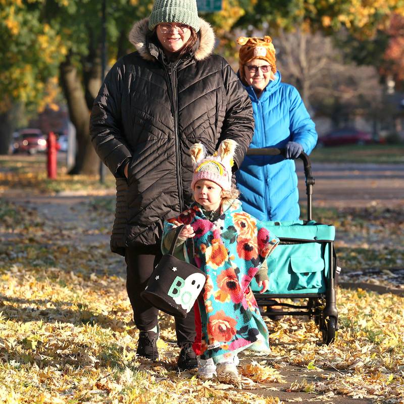 Mabel Leonard, 2, walks with her mom Tabitha Leonard (left) and grandma Jill Newbold as they trick-or-treat on a chilly Halloween Tuesday, Oct. 31, 2023, in DeKalb.