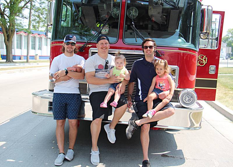 Sterling firefighters Nick Hammer (left), Eric Behrens and Alex Vlakancic sit with their children Asher Hammer, 3 weeks, Lennon Behrens, 2, and Mariana Vlakancic, 3, during a touch-a-truck event at a Juneteenth celebration Saturday, June 17, 2023 in Sterling.