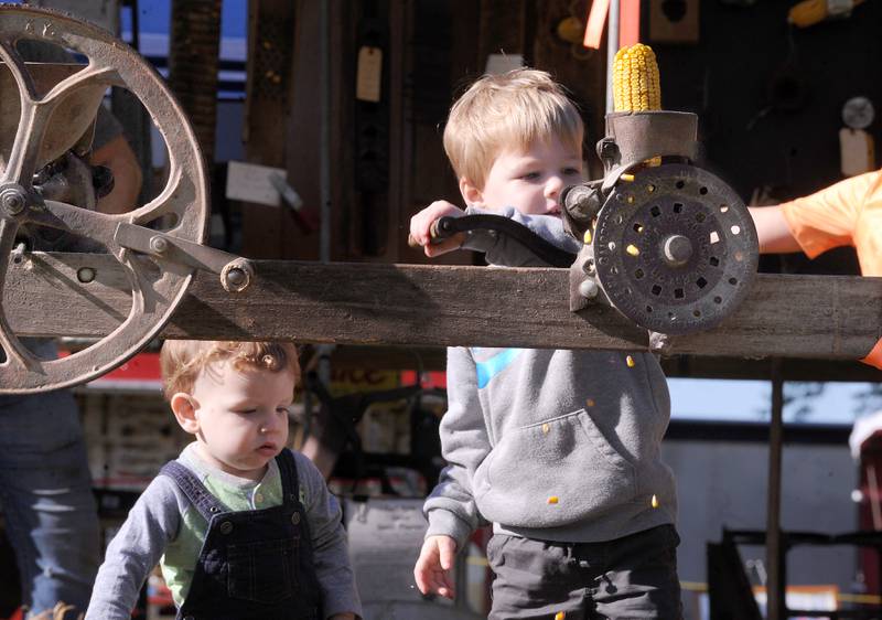 While his brother, 1-year-old Kellen watches, 3-year-old Liam Rogers of Hinckley de-kernels an ear of corn during the Sandwich Fair on Saturday, Sept. 9, 2023.