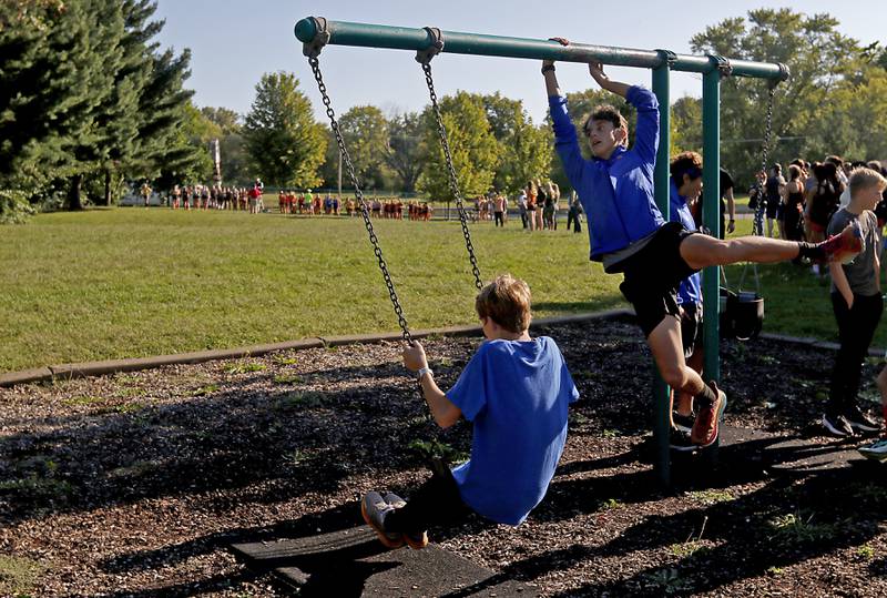 Runners play on the swing set before he start of the girls race of the McHenry County Cross Country Invite on Saturday, August 31, 2024, at McHenry Township Park in Johnsburg.