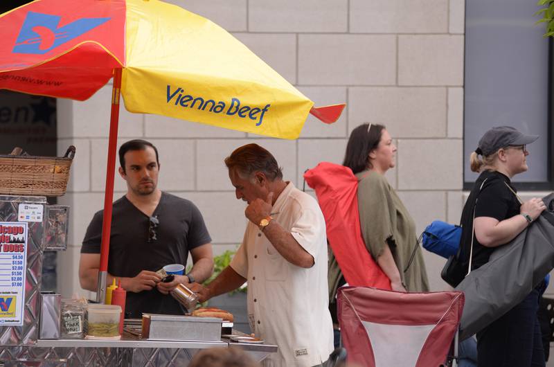 Joe Snellgrove of St. Charles gets a hot dog from Phil Martino of Glen Ellyn during the concert held downtown Glen Ellyn Friday June 8, 2024.