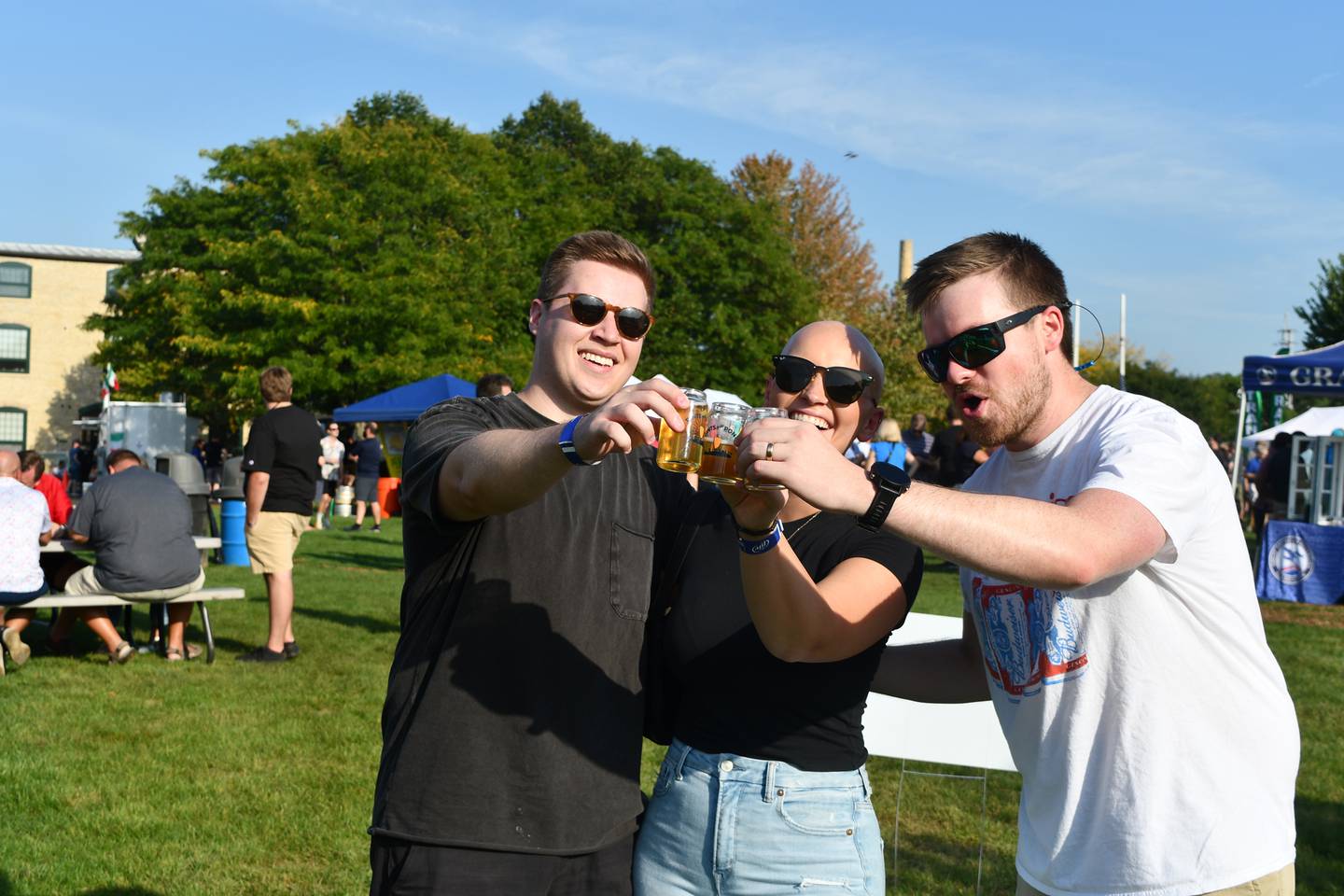 Three attendees at a past Pints by the Pond festival click their beer-tasting glasses together. The 2024 festival will feature over a dozen breweries, as well as two new ones.