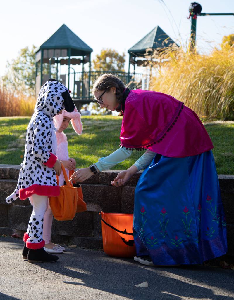 Alyssa Cotter, right, of St. Charles hands candy to Maya (5) and Annie (3) Gonzalez during Boo Bash at the Glen Ellyn Park District on Saturday, Oct. 22, 2022.