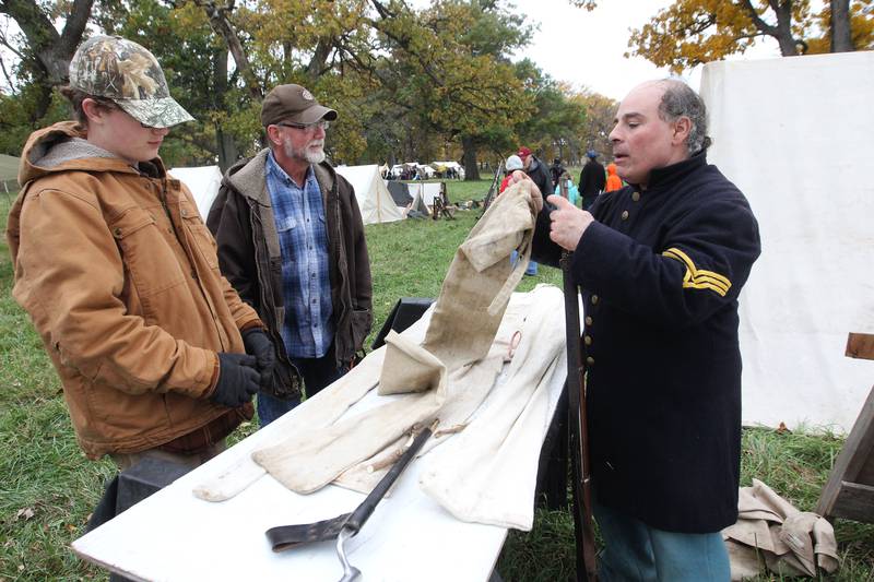 Quinn Anderson, 13, of McHenry and his father, Jeffrey, talk to Joel Calicchio, of Rolling Meadows as he puts away an 1863 Norridge contract rifle he had on display during Hainesville’s Civil War Encampment & Battle at the Northbrook Sports Club on October 21st in Hainesville. 
Photo by Candace H. Johnson for Shaw Local News Network