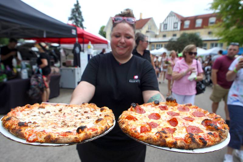 Cory Brown navigates the crowd as she delivers pizzas for her team at the Sweet Natured Pet booth as part of The Dole Farmers Market in Crystal Lake Sunday.