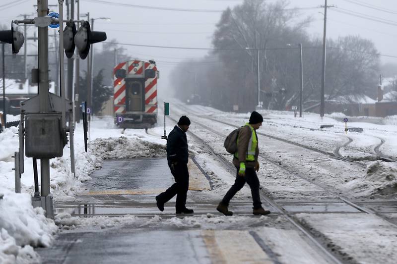 Two men cross the Metra train tracks at the Downtown Crystal Lake Metra station on Tuesday, Jan. 23, 2023. Residents throughout northern Illinois woke up to icy and slippery roads.